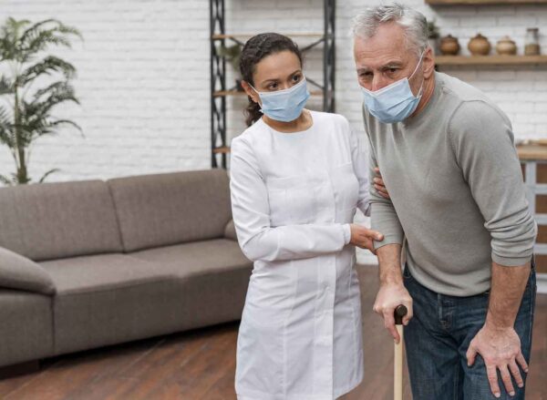 young beautiful woman with long wavy hair wearing apron and rubber gloves holding rug and cleaning spray looking confident and positive smiling showing thumbs up ready to clean standing over blue b